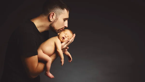 Bebê recém-nascido nas mãos de seu pai no escuro — Fotografia de Stock