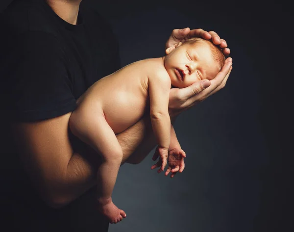 Nyfödd baby i sin fars händer i mörkret — Stockfoto