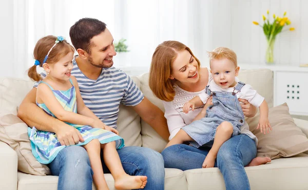 Feliz familia riendo y abrazándose en casa en el sofá —  Fotos de Stock