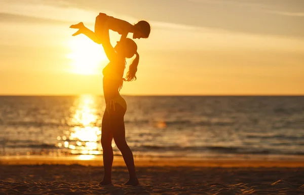 Gelukkige familie moeder gooit up kind dochter op strand in summe — Stockfoto