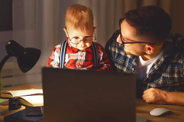 Padre e hijo bebé trabajo en casa en la computadora en la oscuridad —  Fotos de Stock