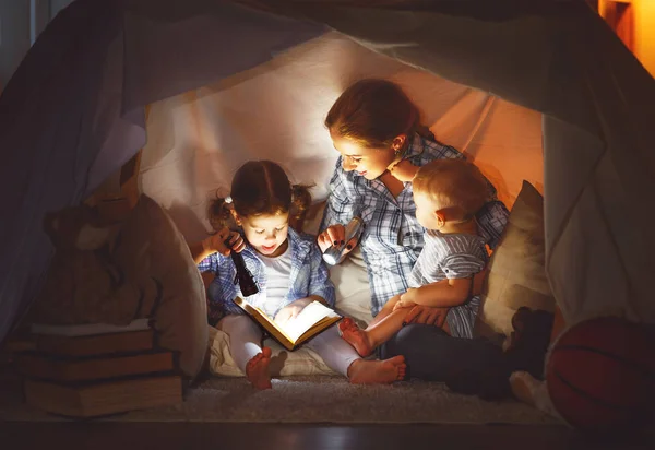 Família feliz mãe e crianças lendo um livro na tenda em hom — Fotografia de Stock