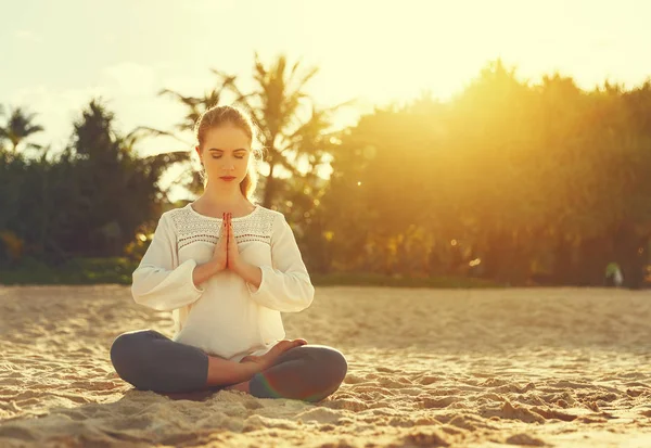 Kvinna praktiserar yoga och mediterar i lotusställning på stranden — Stockfoto