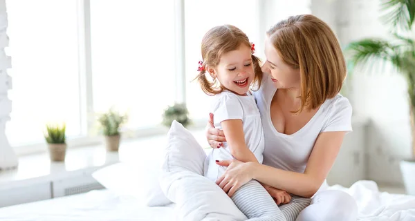 Happy family mother and child daughter laugh in be — Stock Photo, Image