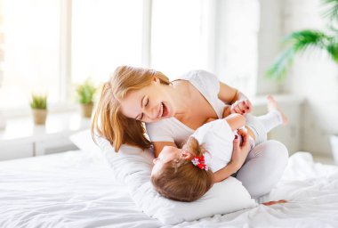 Mutlu aile anne ve çocuk kızı yatakta gülmek