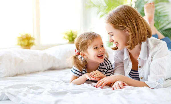 Lyckliga familjen mor och barn dotter skratta i sängen — Stockfoto