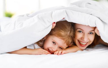 Mutlu aile anne ve çocuk kızı yatakta gülmek