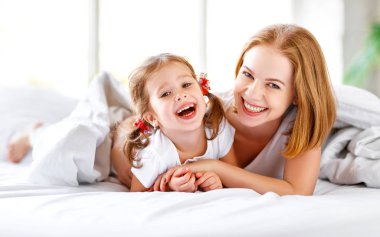 Mutlu aile anne ve çocuk kızı yatakta gülmek