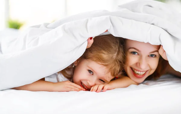 Счастливая семья мать и ребенок дочь смеются в постели — стоковое фото