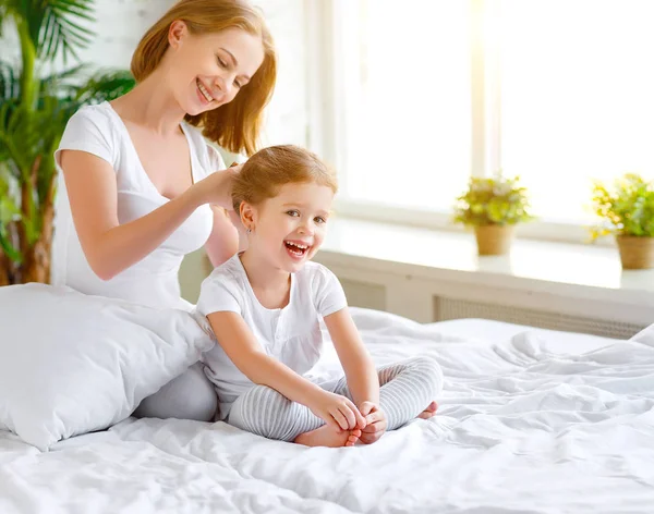 Мати розчісує дочку в ліжку — стокове фото