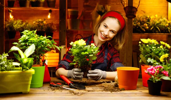 Glückliche Gärtnerin pflanzt um und gießt Blumen — Stockfoto