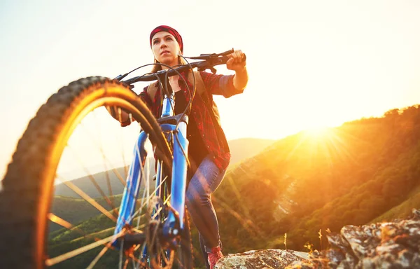 Woman tourist on a bicycle at top of mountain at sunset outdoors — Stock Photo, Image