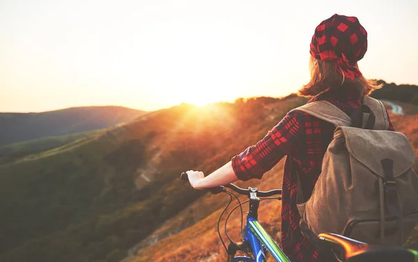 Mulher turista em uma bicicleta no topo da montanha ao pôr do sol ao ar livre — Fotografia de Stock