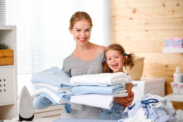 Happy family mother housewife and child daughter ironing clothes — Stock Photo, Image