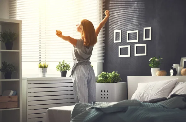 Fiatal nő ébredt fel reggel a hálószobában által a windo — Stock Fotó