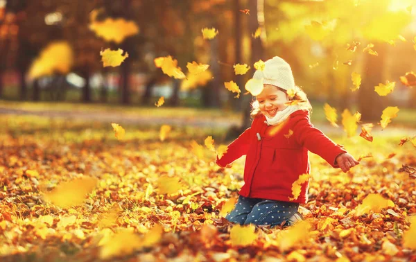 Happy child girl throws autumn leaves and laughs — Stock Photo, Image