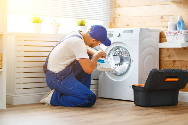 Trabalho homem encanador reparos máquina de lavar roupa na lavanderia — Fotografia de Stock