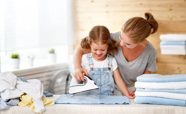 Щаслива сім'я домогосподарка і дочка, що прасує одяг — стокове фото