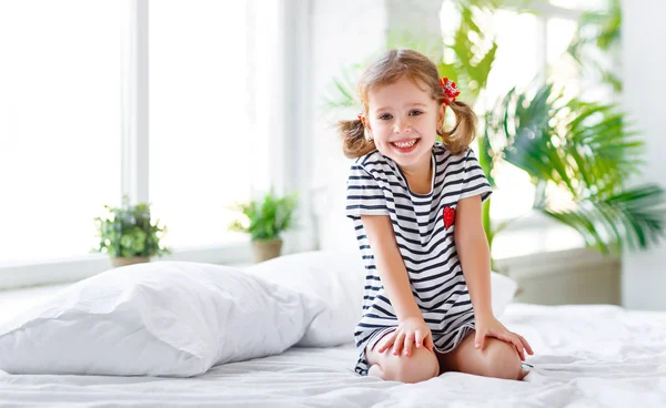 Glückliches Kindermädchen lächelt im Bett — Stockfoto