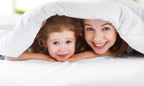 Família feliz mãe e criança filha rir na cama — Fotografia de Stock