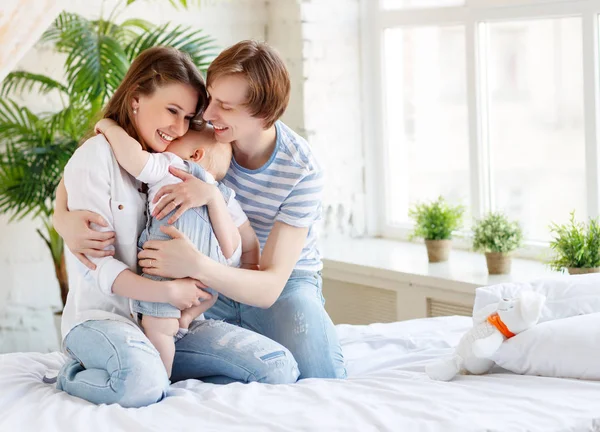 Família feliz mãe pai e bebê na cama — Fotografia de Stock