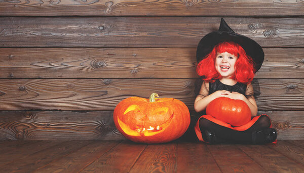 happy child girl in costume witch for Halloween with pumpkins   