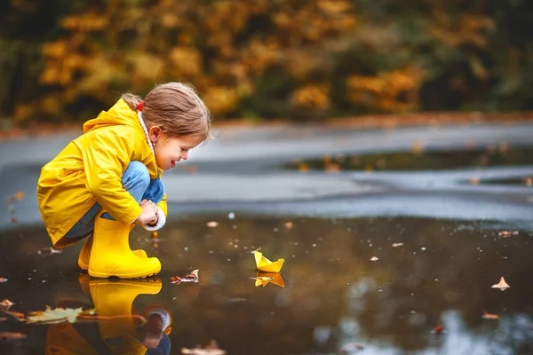 Gelukkig kind meisje met papier boot in plas in de herfst op natu — Stockfoto