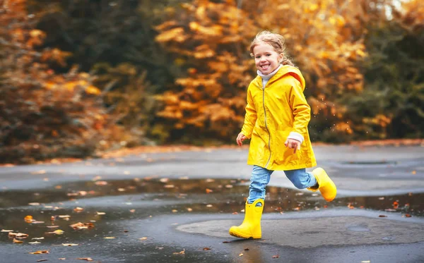 Menina feliz criança com um guarda-chuva e botas de borracha na poça em — Fotografia de Stock