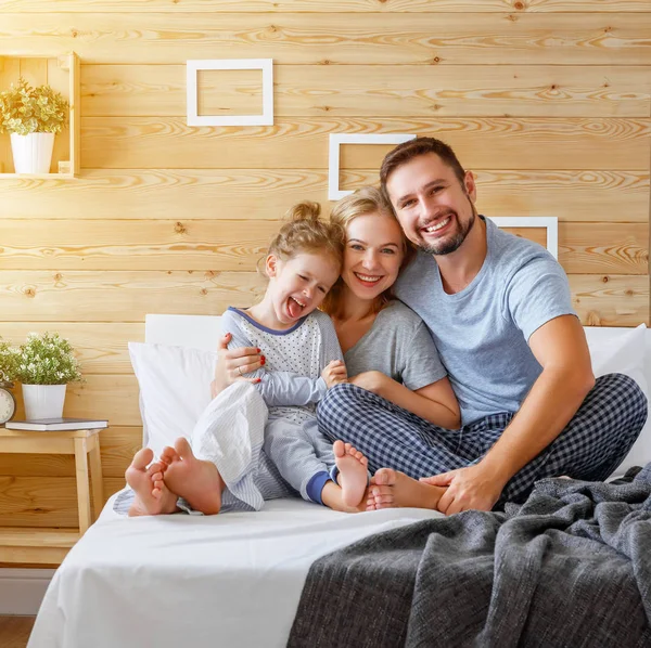 Boldog család anya, apa és a gyermek nevet az ágyban — Stock Fotó