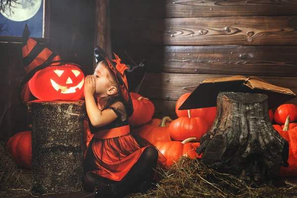 Хэллоуин. маленькая ведьма колдует с книгой заклинаний, магии — стоковое фото
