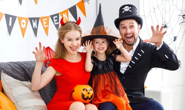 Счастливая семья в костюмах готовится к Хэллоуину дома — стоковое фото