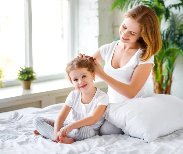 Mãe pentear cabelo filha na cama — Fotografia de Stock
