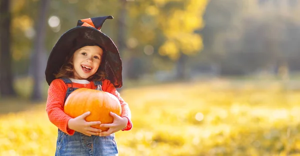 Child girl with pumpkin outdoors in halloween — Stock Photo, Image