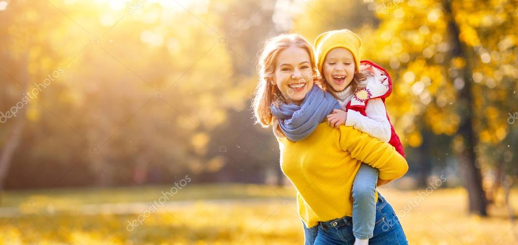 Happy family mother and child daughter playing and laughing on   autumn walk