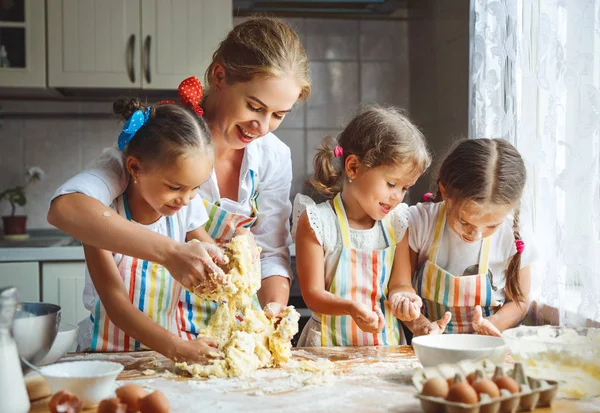 Счастливая семья мать и дети близнецы выпекать тесто в — стоковое фото