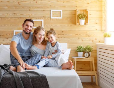 yatakta mutlu aile anne, baba ve çocuk gülüyor