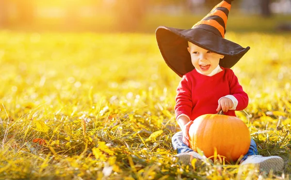 Babyjongen met pompoen buitenshuis in halloween — Stockfoto