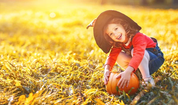 Menina criança com abóbora ao ar livre no dia das bruxas — Fotografia de Stock
