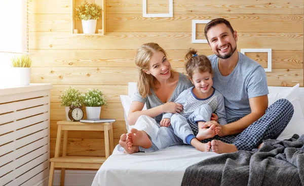 Gelukkige familie moeder, vader en kind lacht in bed — Stockfoto