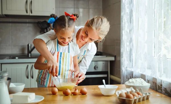 Счастливая семья мать и дочь пекут тесто на кухне — стоковое фото