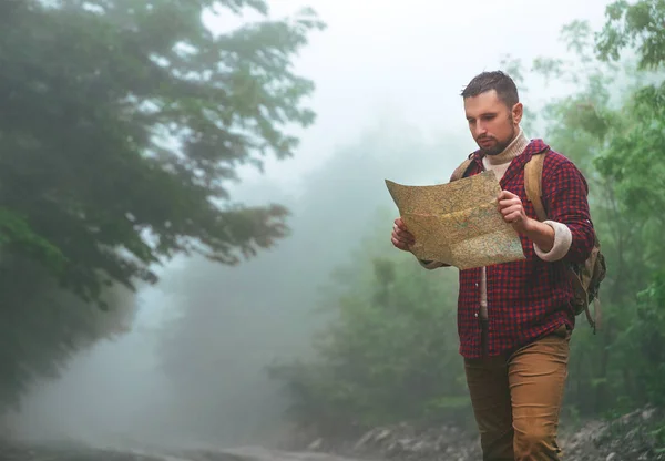 Mužské turista v lesích v horách s mapou — Stock fotografie