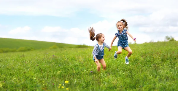 Счастливые дети близнецы сестры прыгать и смеяться летом — стоковое фото