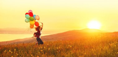 Sunse, çayır boyunca çalışan balonlar ile mutlu neşeli kız