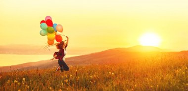 Sunse, çayır boyunca çalışan balonlar ile mutlu neşeli kız