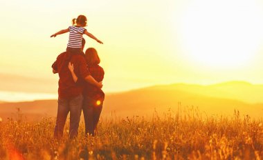Mutlu bir aile: anne baba ve çocuk kız günbatımı üzerinde