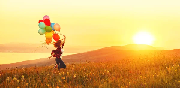 Happy cheerful girl with balloons running across meadow at sunse — Stock Photo, Image