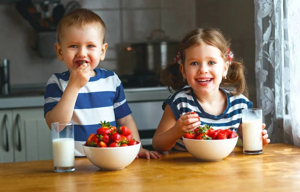 Bambini felici fratello e sorella mangiare fragole con latte — Foto Stock