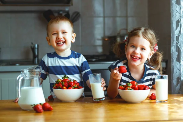 Щасливі діти брат і сестра їдять полуницю з молоком — стокове фото