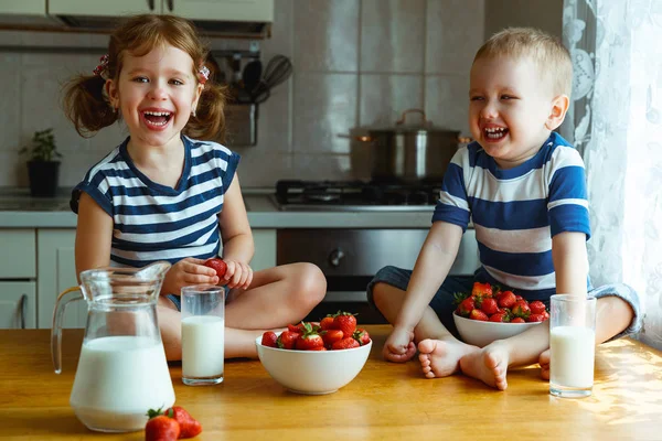 Счастливые дети брат и сестра едят клубнику с молоком — стоковое фото