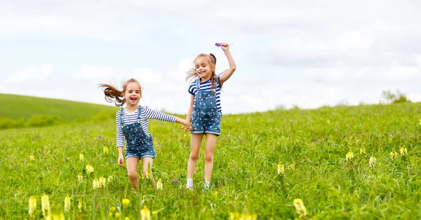 Szczęśliwe dzieci siostry bliźniaczki skoki i śmiejąc się latem — Zdjęcie stockowe